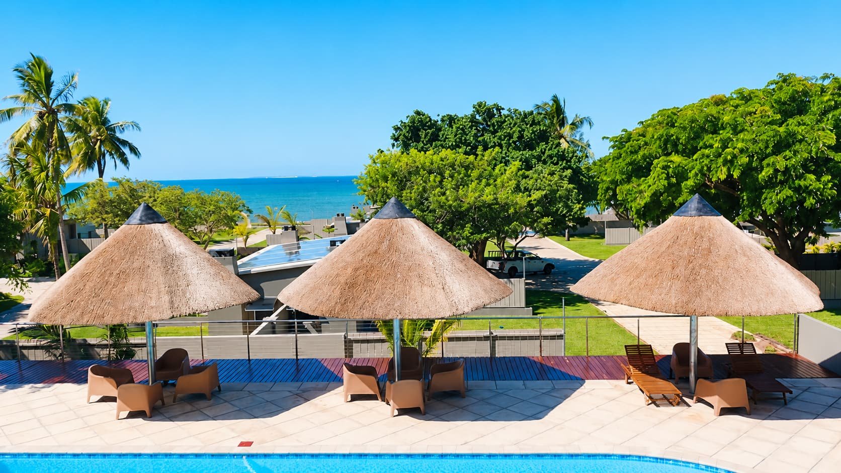 Thatched pool umbrellas and loungers with the ocean beyond