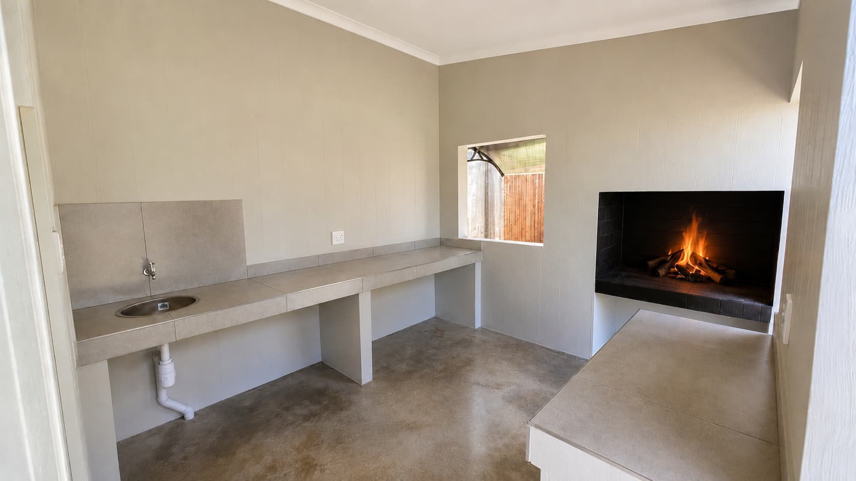 Indoor braai room with a lit fireplace and kitchenette counter on a Premium stand