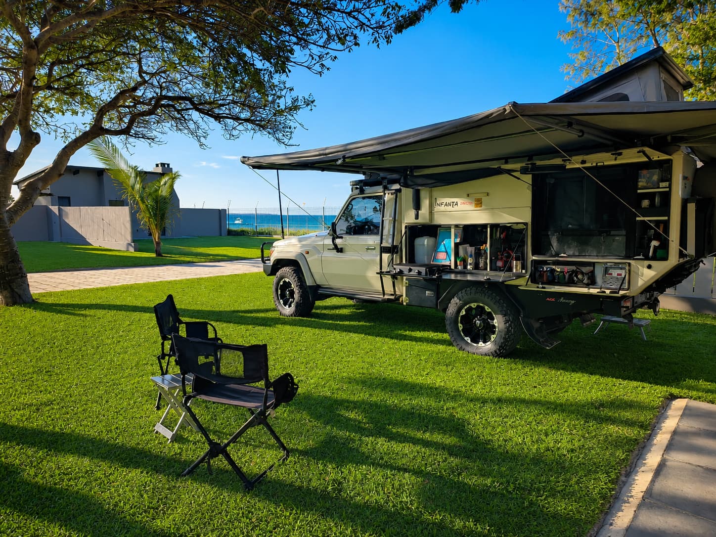 Overland camper with awning and camp chairs set up on a Premium stand