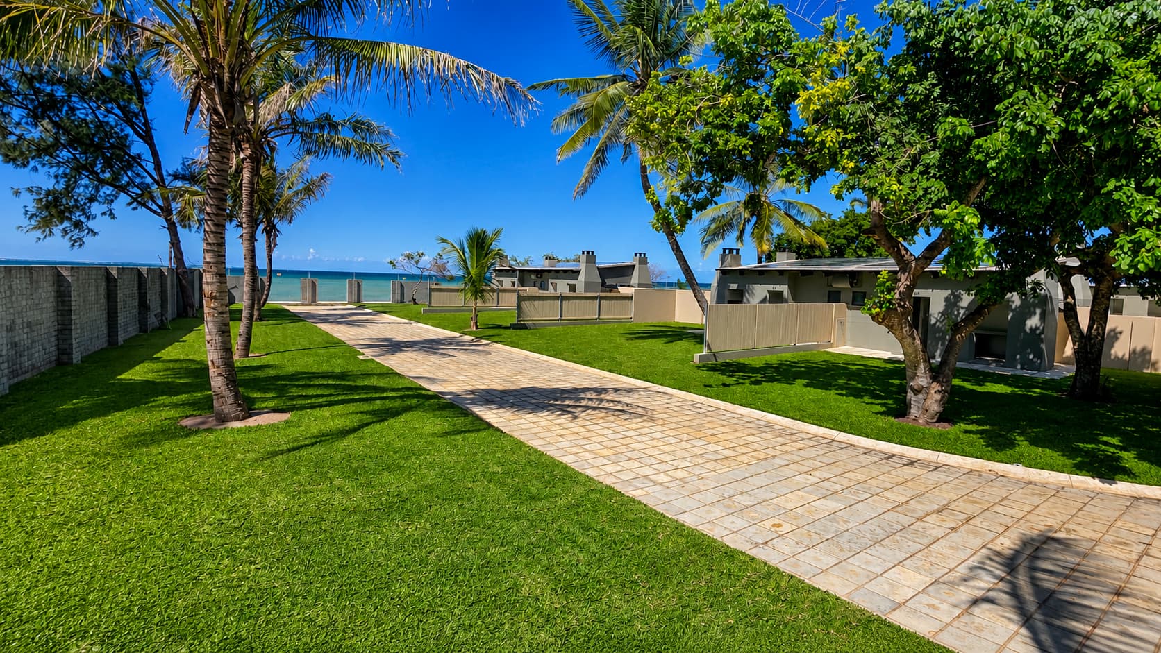 Paved pathway between grassed stands leading toward the ocean