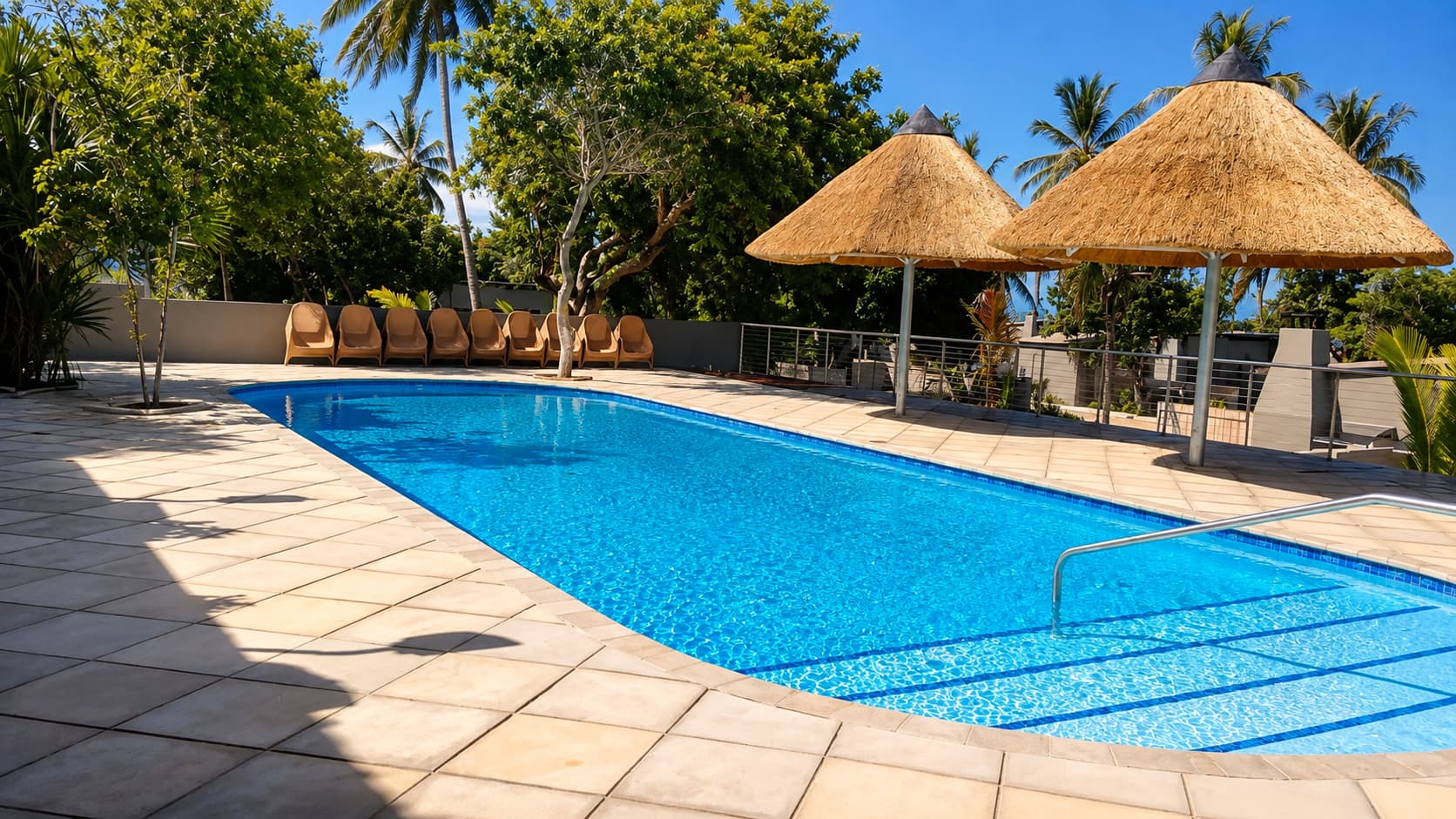 Campsite swimming pool with thatched shade umbrellas and loungers