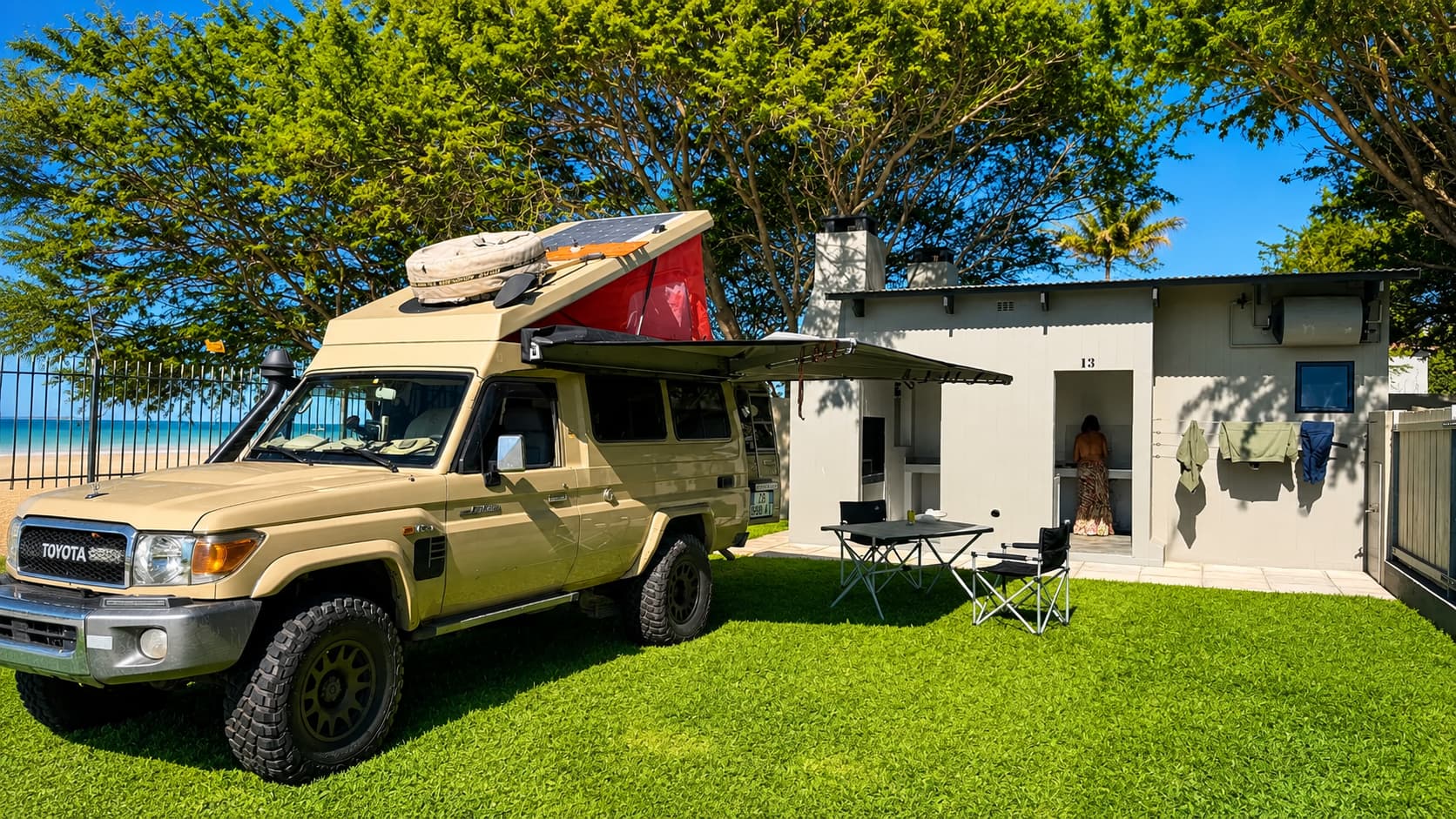 Overland camper truck with rooftop tent set up on a grassed stand