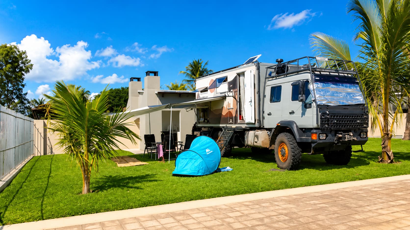 Overland camper with awning set up beside a stand