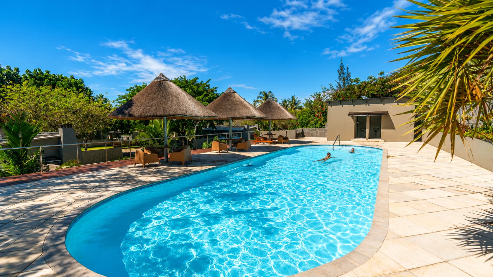 Campsite swimming pool with thatched gazebos alongside